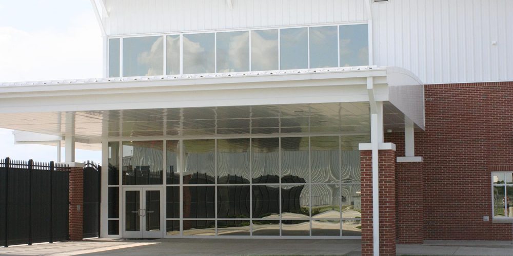 Exterior view of front entry of Becks Airport; glass door entry inside large window wall