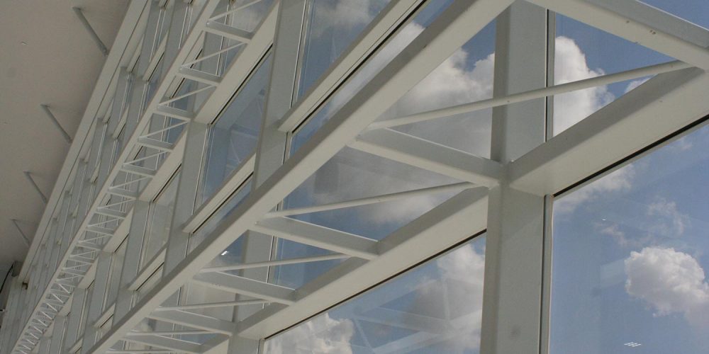 Close up of large window wall at Becks Airport; puffy white clouds visible outside