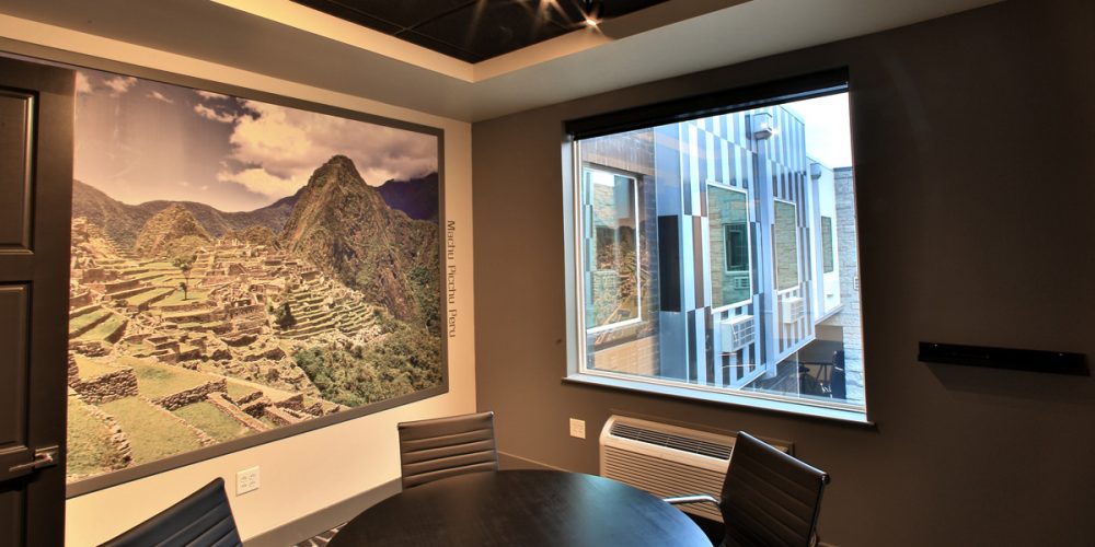 Interior view of conference room with large photo of Machu Picchu and large window looking out at unique exterior windows and courtyard