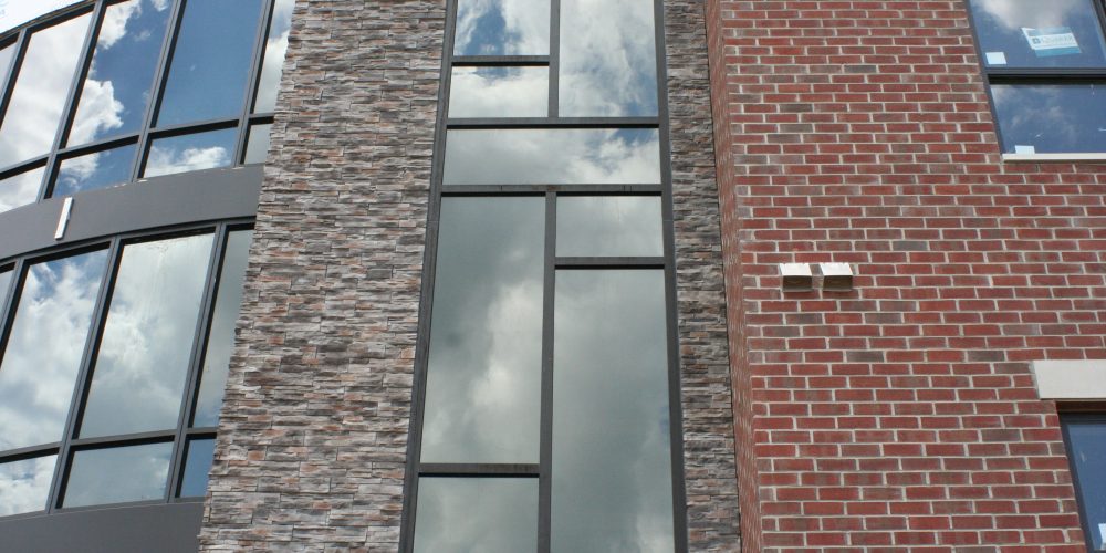 Exterior view of brick and stone building with curved glass window wall